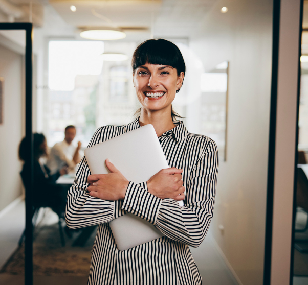 Smiling businesswoman holding a laptop at work 1