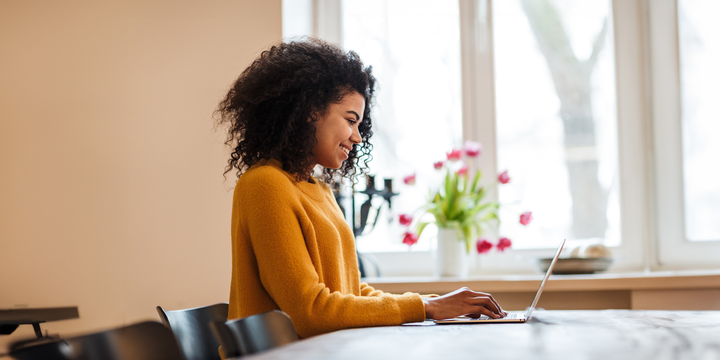 african american woman using laptop while sitting at table