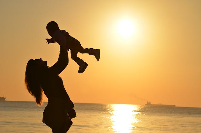 mother holding baby on beach