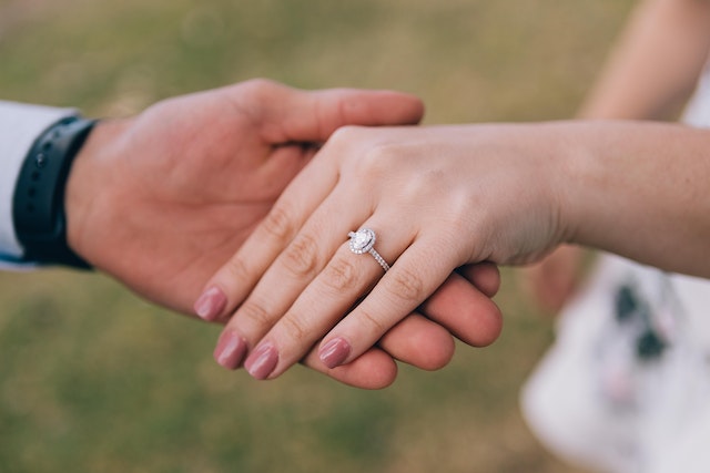 couple holding hands with engagement ring on