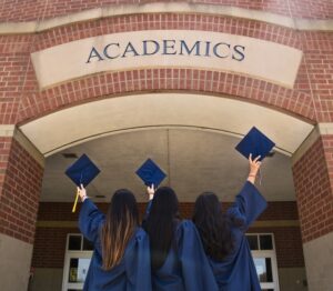 three girls holding graduation hats in front of 