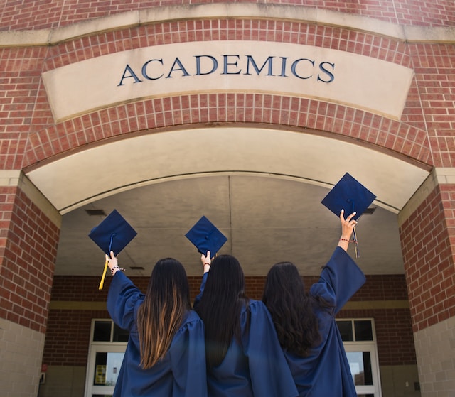 three girls holding graduation hats in front of 