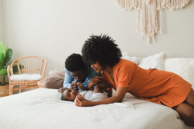 parents laying on bed with baby