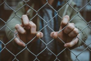 person grabbing chain link fence