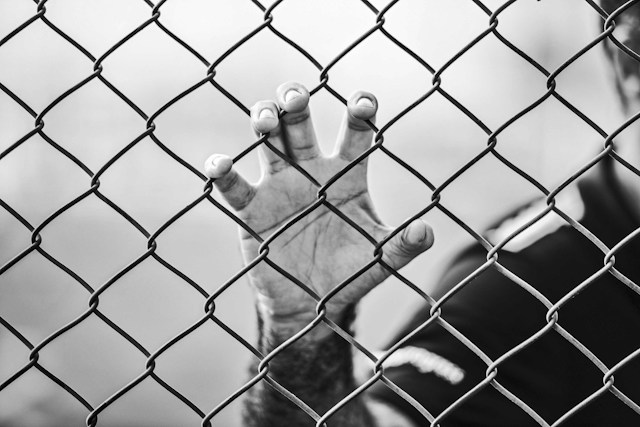 person holding chain link fence