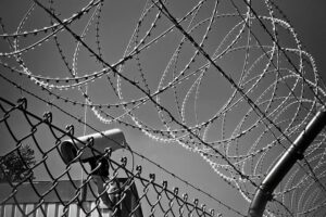 bared wire atop fence with security camera