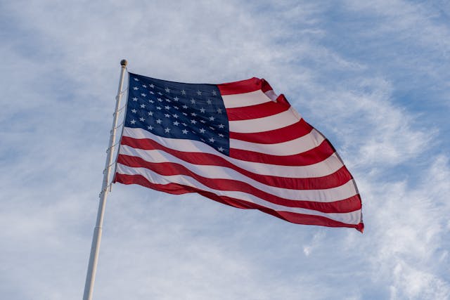 american flag on pole against clouds